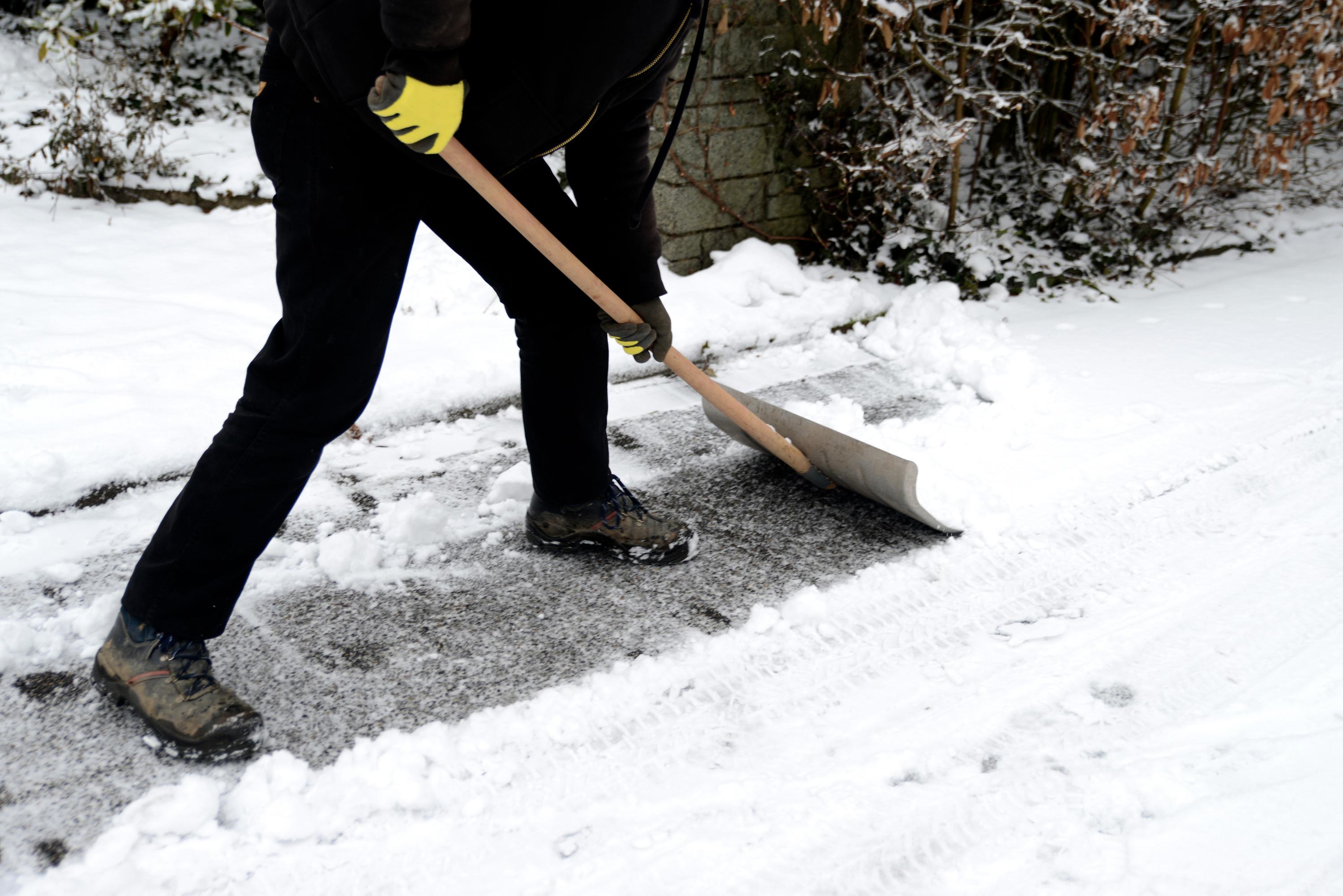 Personne retirant la neige de son trottoir